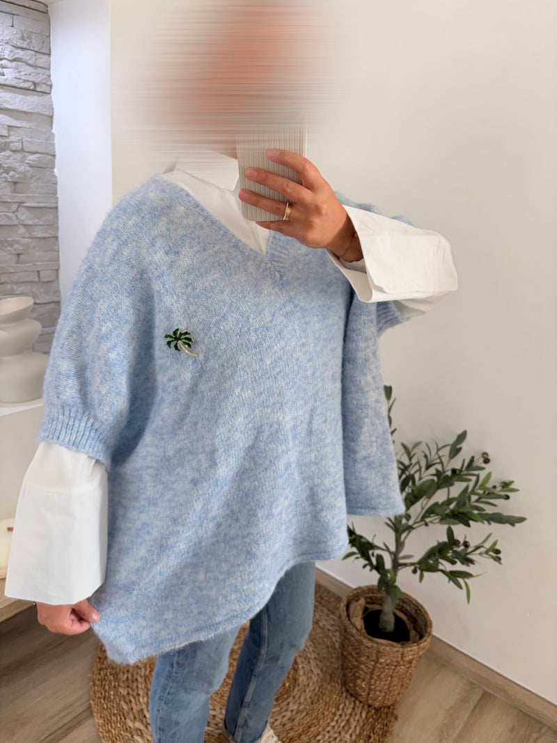 Pull bleu ciel col V à manches ballon, porté sur une chemise blanche
